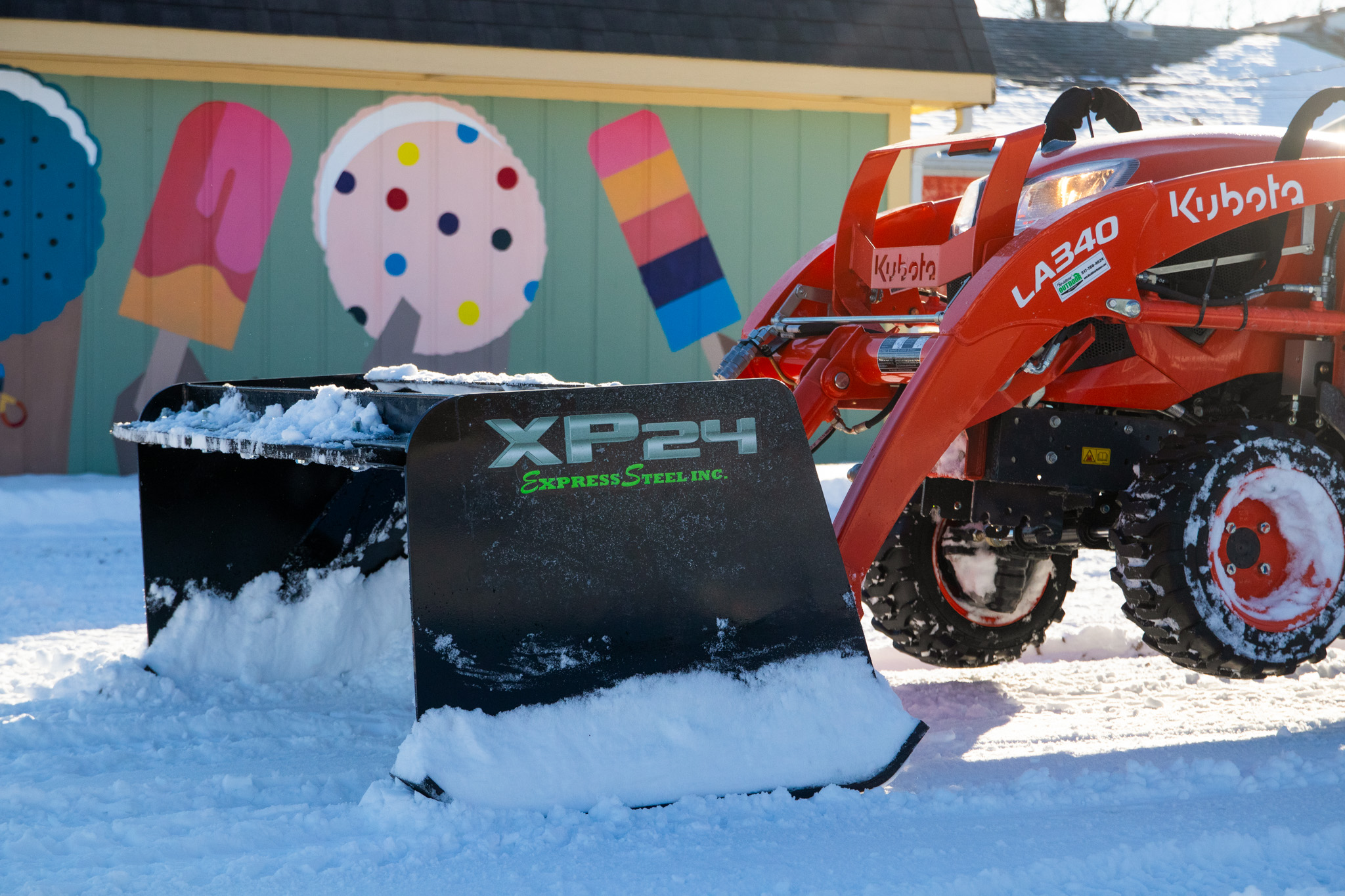 express steel snow pusher pushing snow with compact tractor